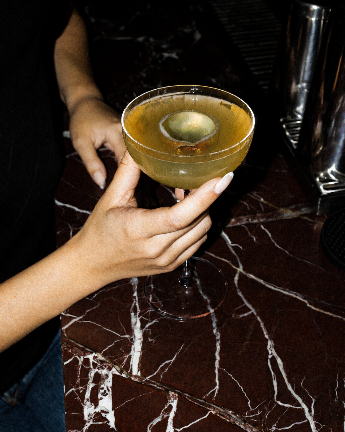 Cocktail signature dans une coupe sur marbre rouge